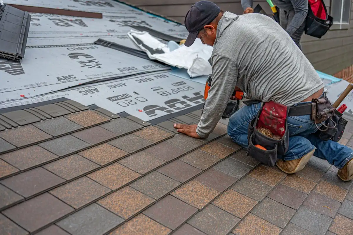 Roofing installer fastening shingles over new underlayment in Cleveland, TN